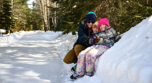 family sitting together in snow bank
